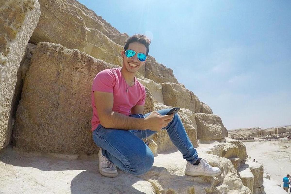 a man sitting on some rocks holding a cell phone