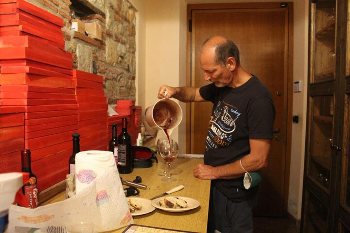 moški stoji v kuhinji in pripravlja kozarec vina