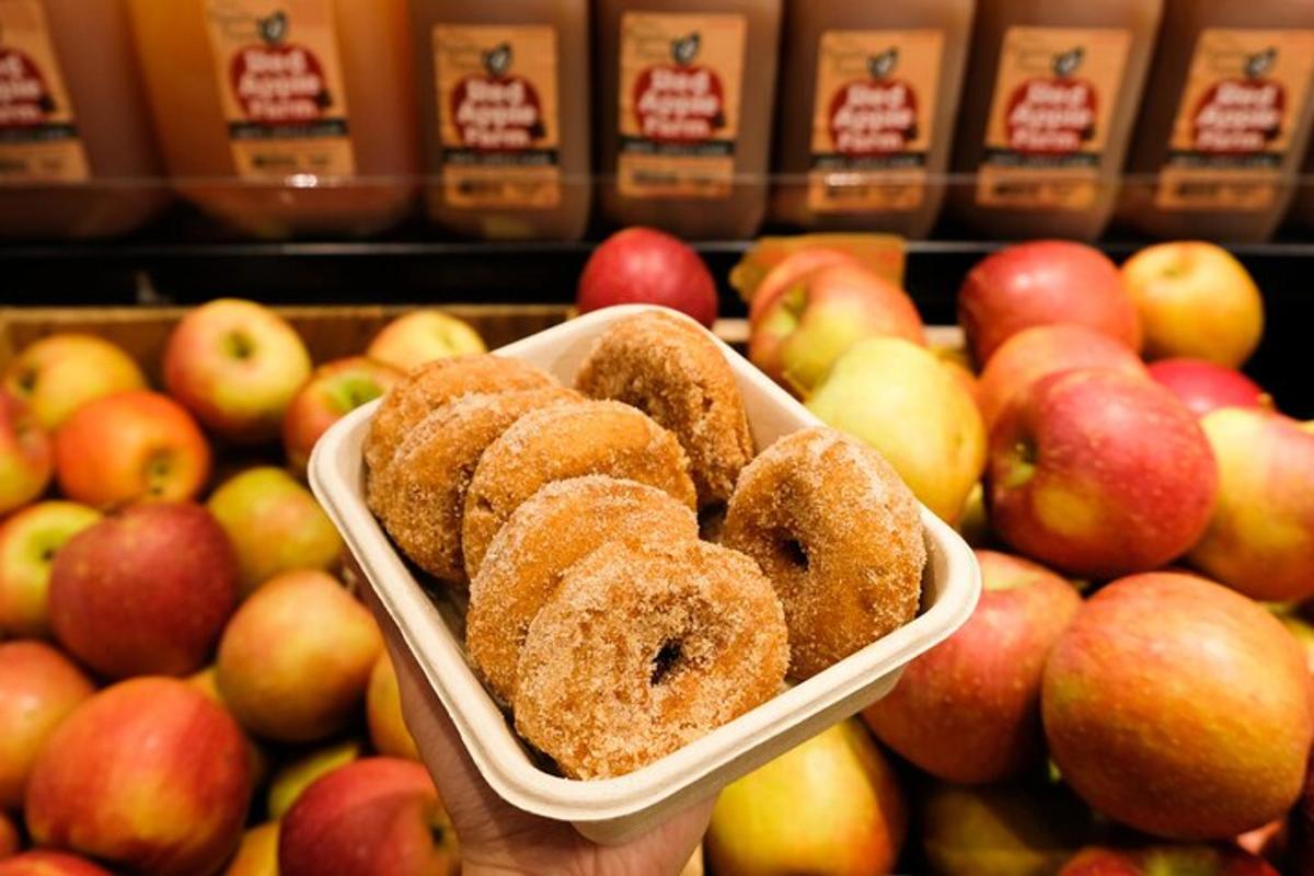 una persona sosteniendo un tazón de donas frente a manzanas