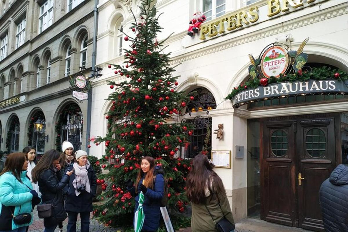 Personas de pie alrededor de un árbol de Navidad frente a un edificio.