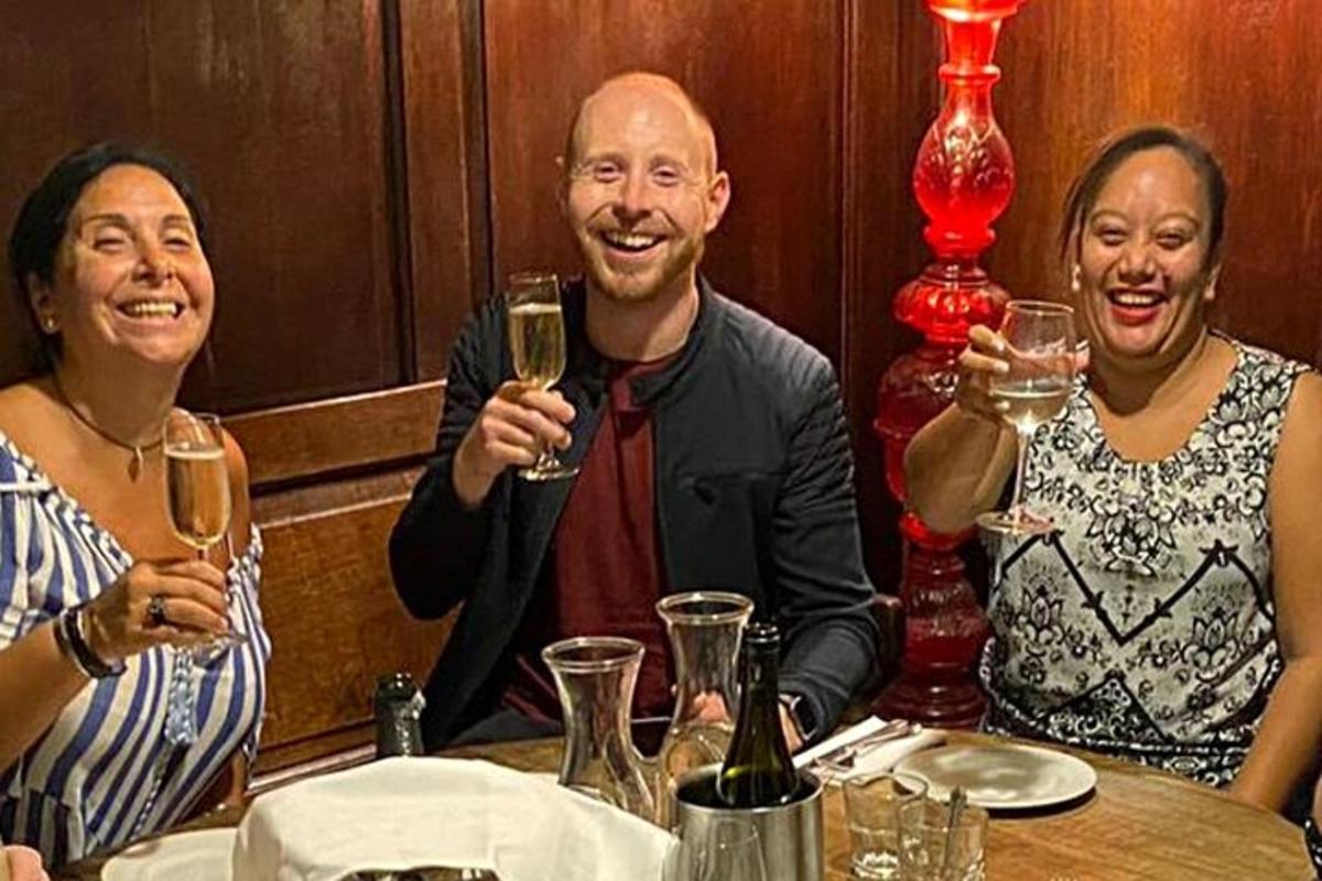 a group of three people sitting at a table with wine glasses