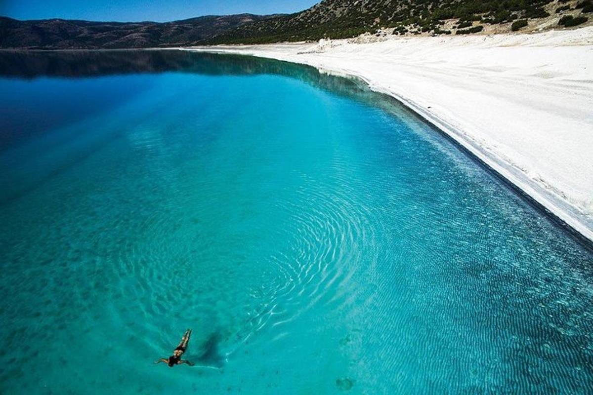 una persona nedant en una massa d'aigua al costat d'una platja