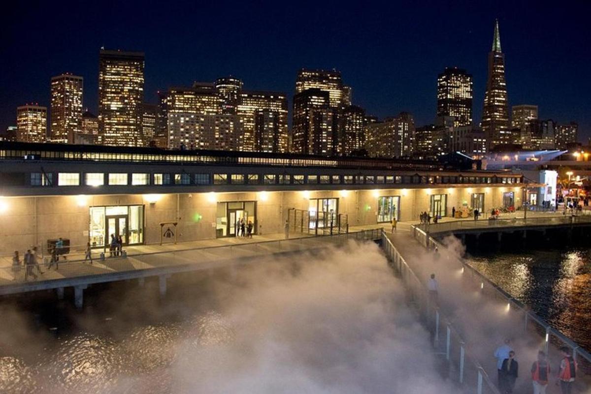 a building with steam in front of a city at night