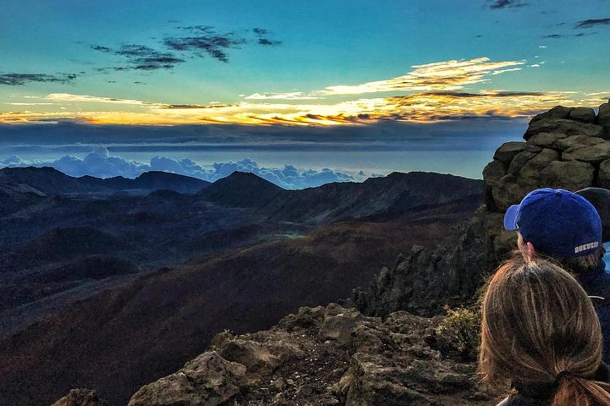 eine Frau, die auf einem Berggipfel sitzt und die Aussicht genießt