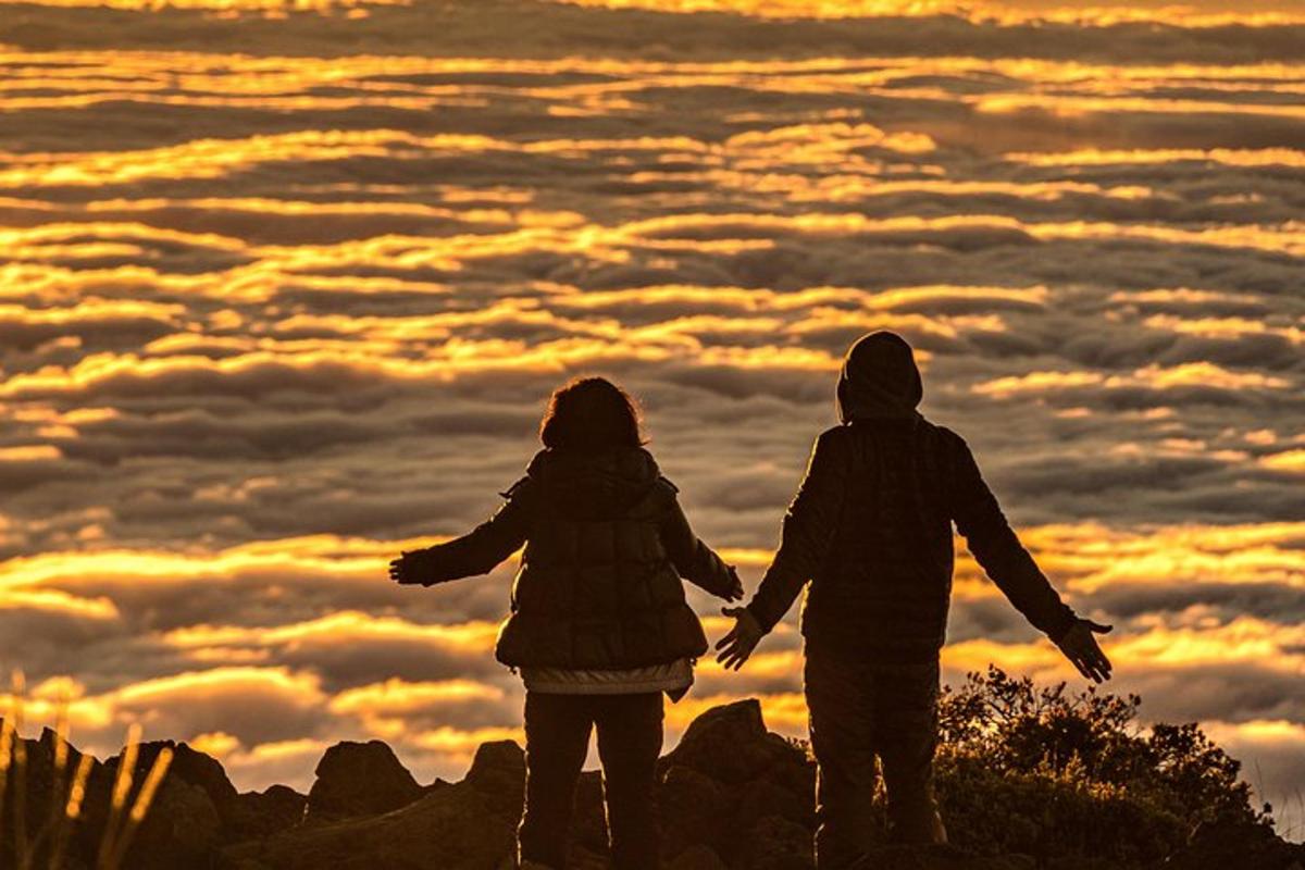 zwei Menschen stehen bei Sonnenuntergang auf einem Berggipfel