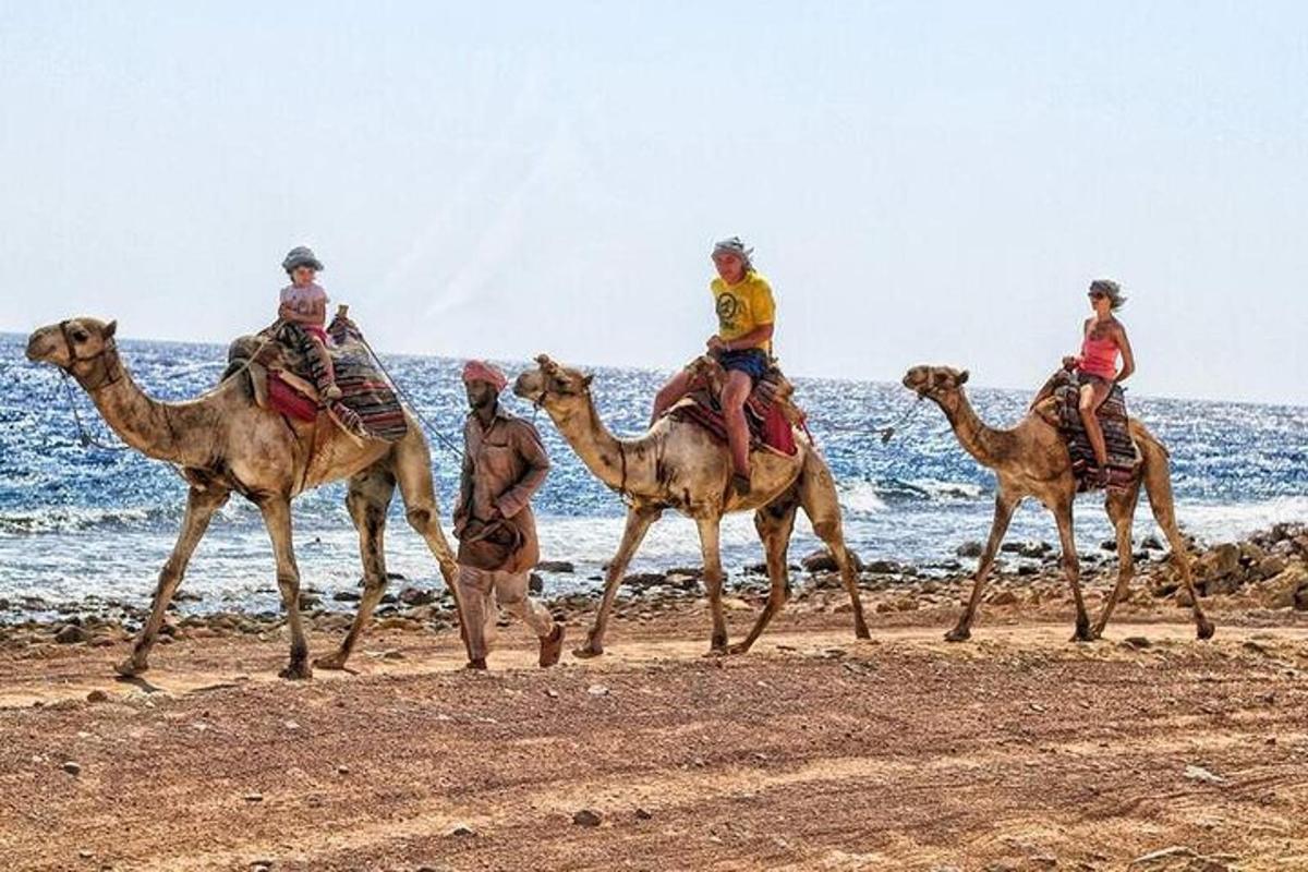 een groep mensen die op kamelen op het strand rijdt