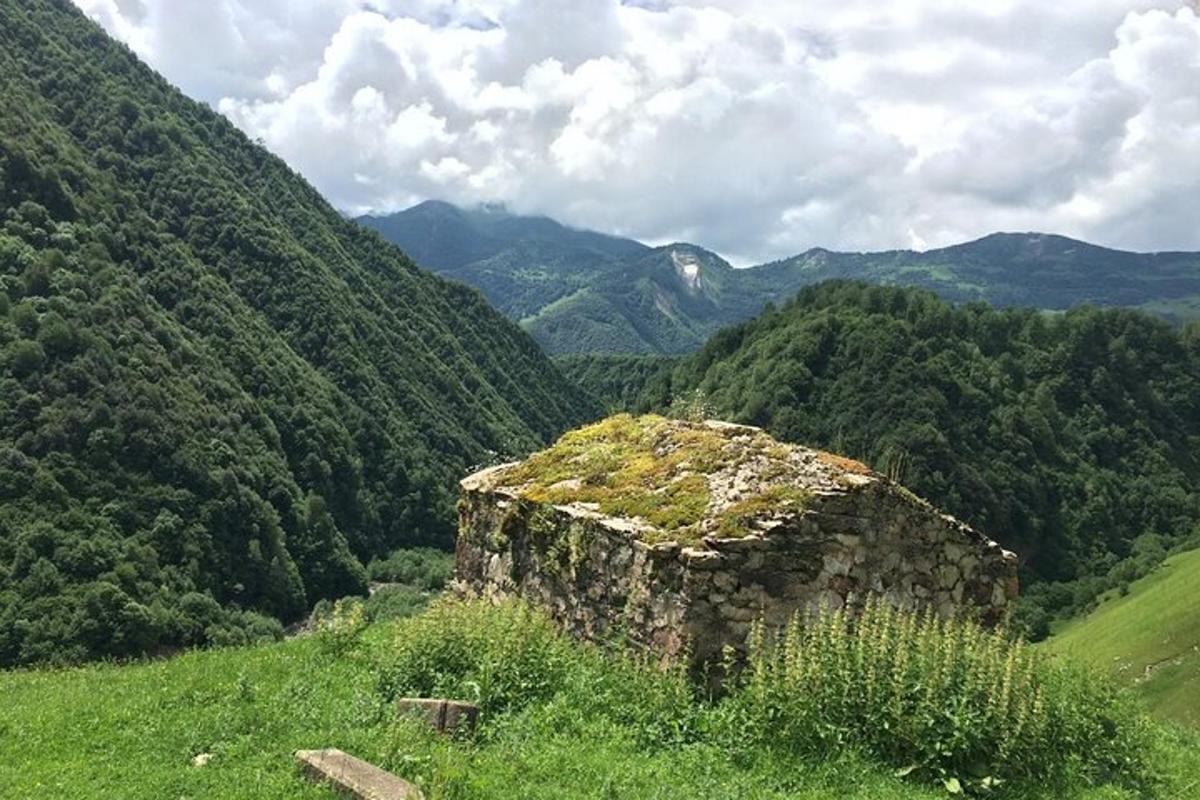 isang lumang gusali sa isang burol na may mga bundok sa background