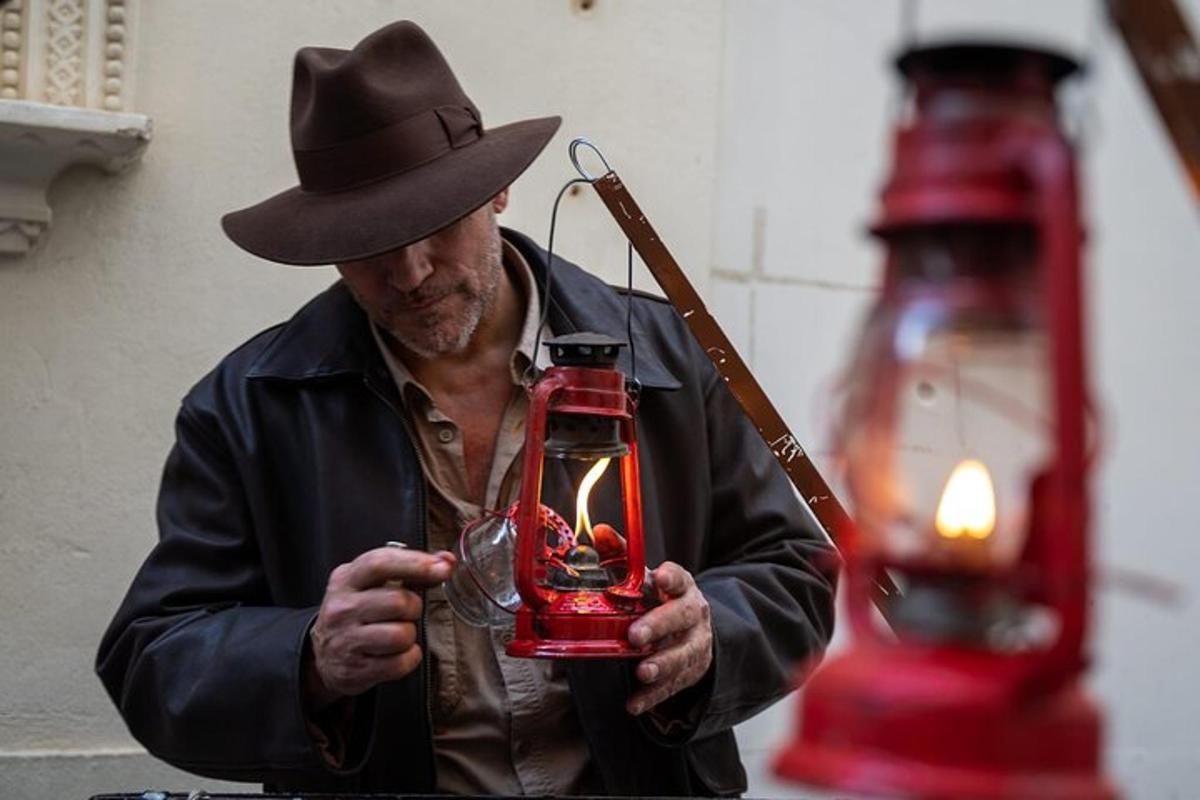 a man wearing a hat holding a glass with a candle