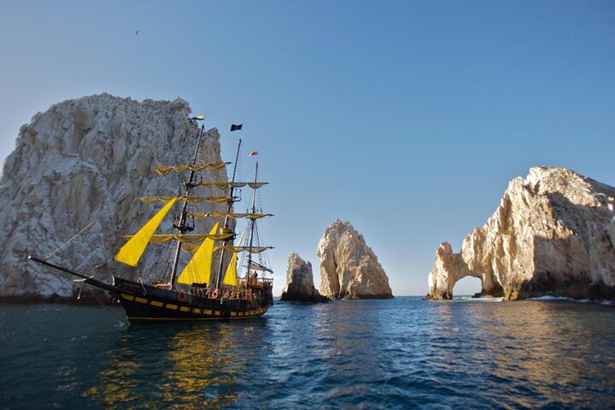 a tall ship in the water near a rock formation