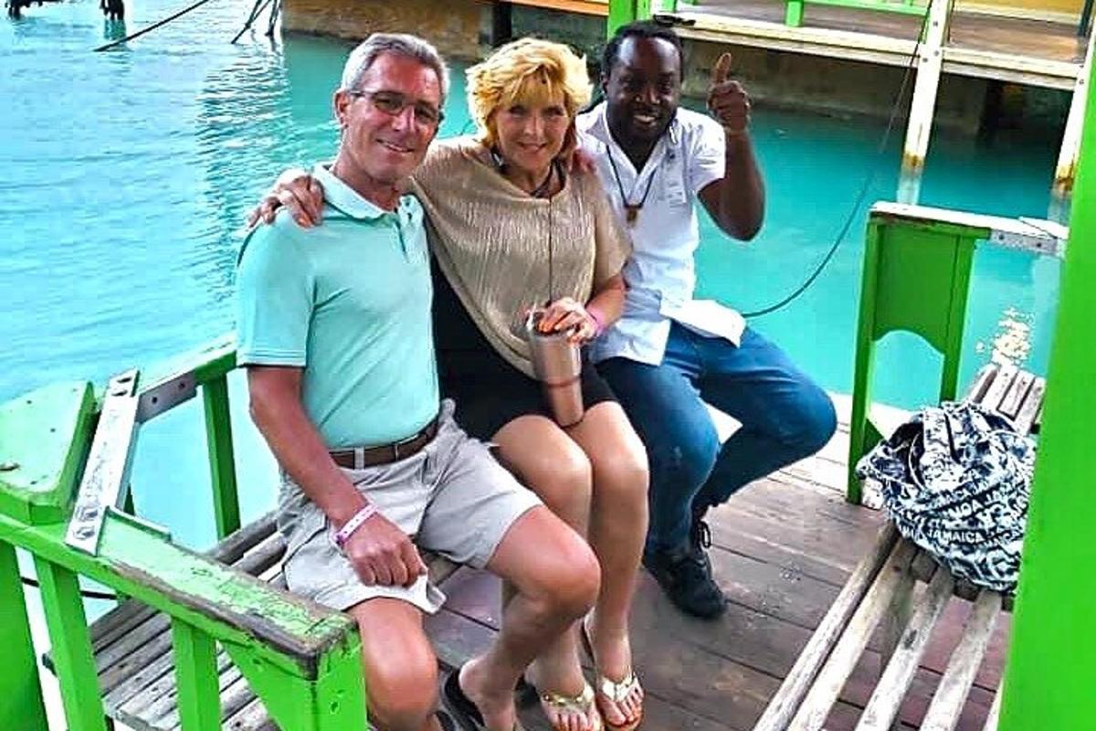 un uomo e una donna seduti su un molo vicino all'acqua
