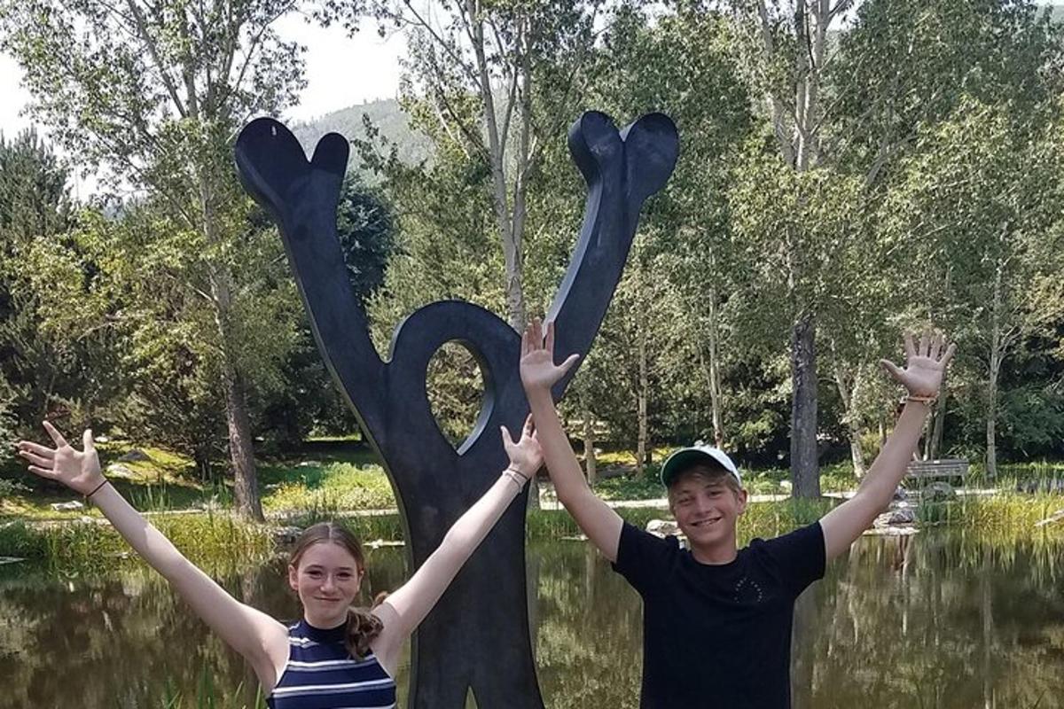 two children are holding their hands up in front of a statue