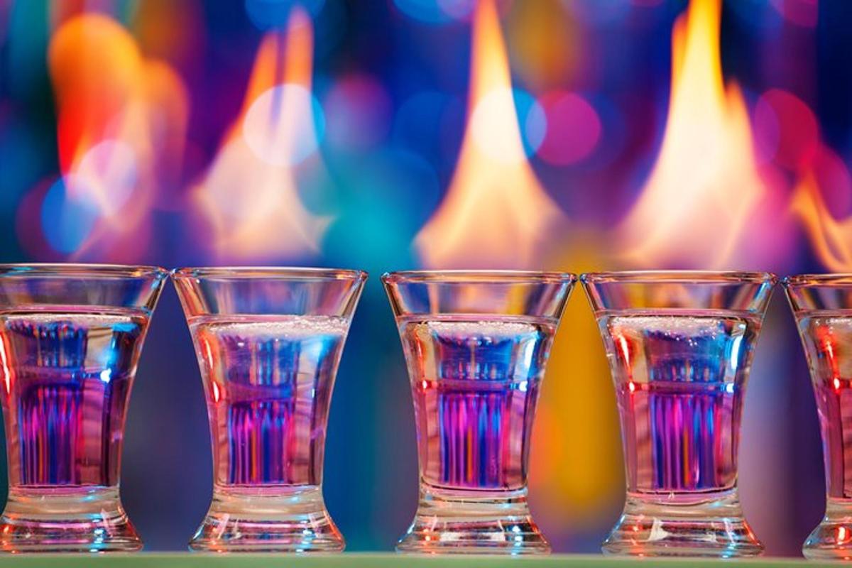 a row of shot glasses with a fire in the background