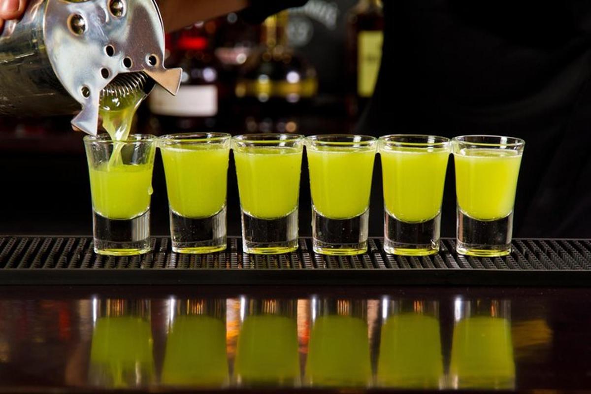 a bartender is preparing a row of green drinks