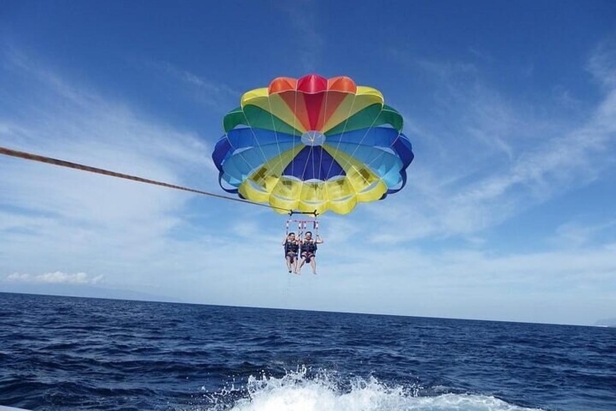 due persone appese a un ombrello colorato sopra l'oceano
