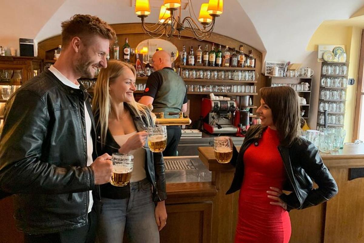 drei Personen stehen mit Gläsern Bier an einer Bar