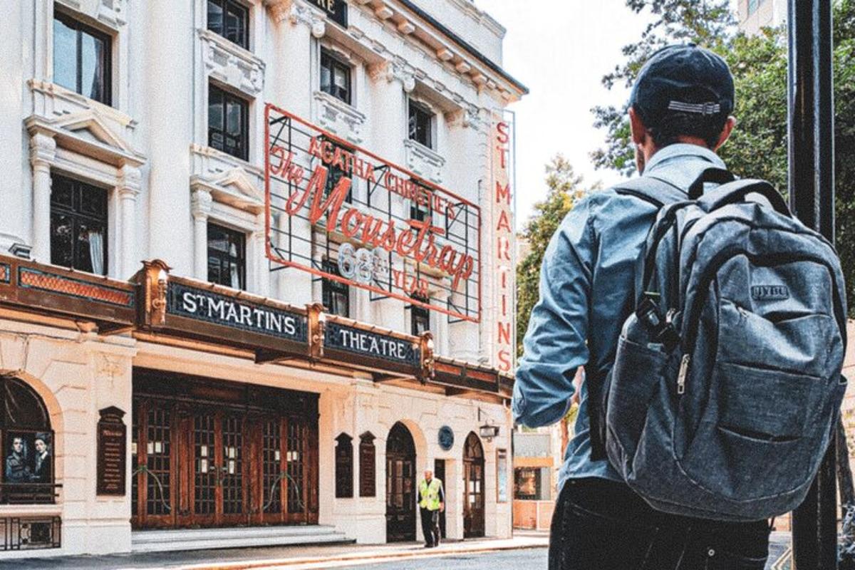 um homem com uma mochila em pé em frente a um prédio