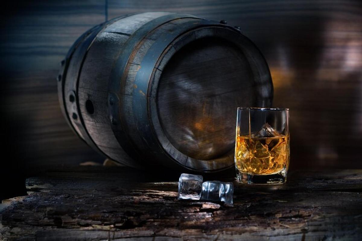sklenice whisky stojící vedle sudu
