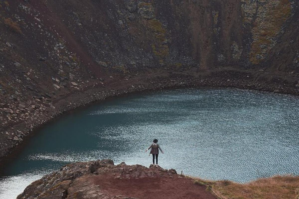 una persona in piedi su una roccia di fronte a un lago