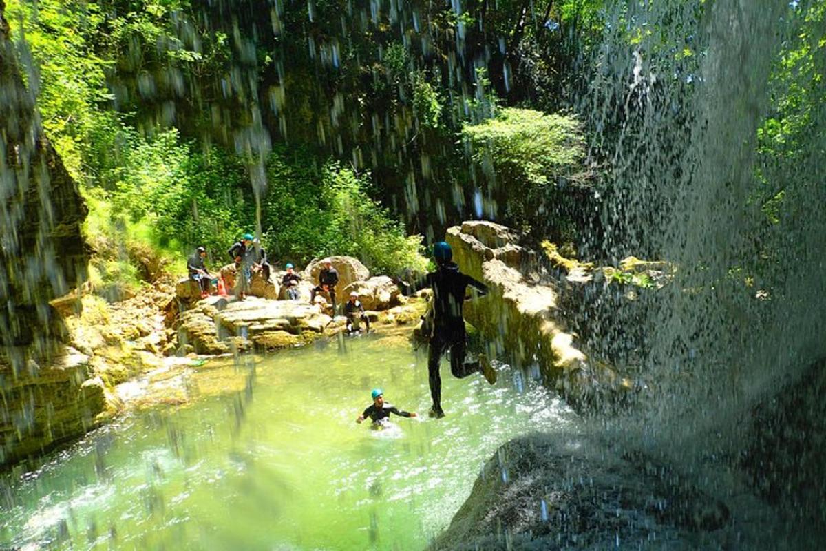 a group of people in the water at a waterfall