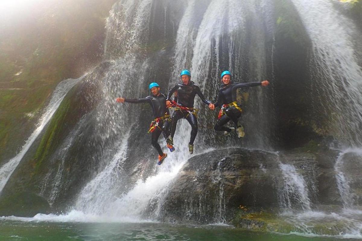 three people jumping off of a waterfall