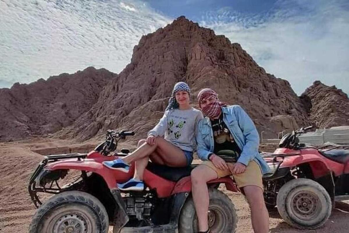 two people sitting on a four wheeler in the desert
