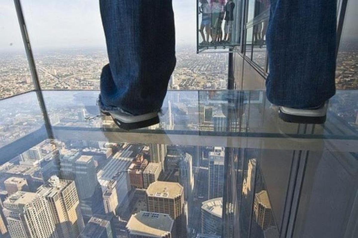 a person standing on the glass floor of a skyscraper