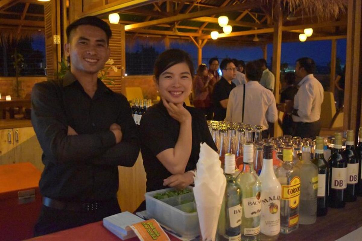seorang pria dan seorang wanita berdiri di samping meja dengan botol anggur