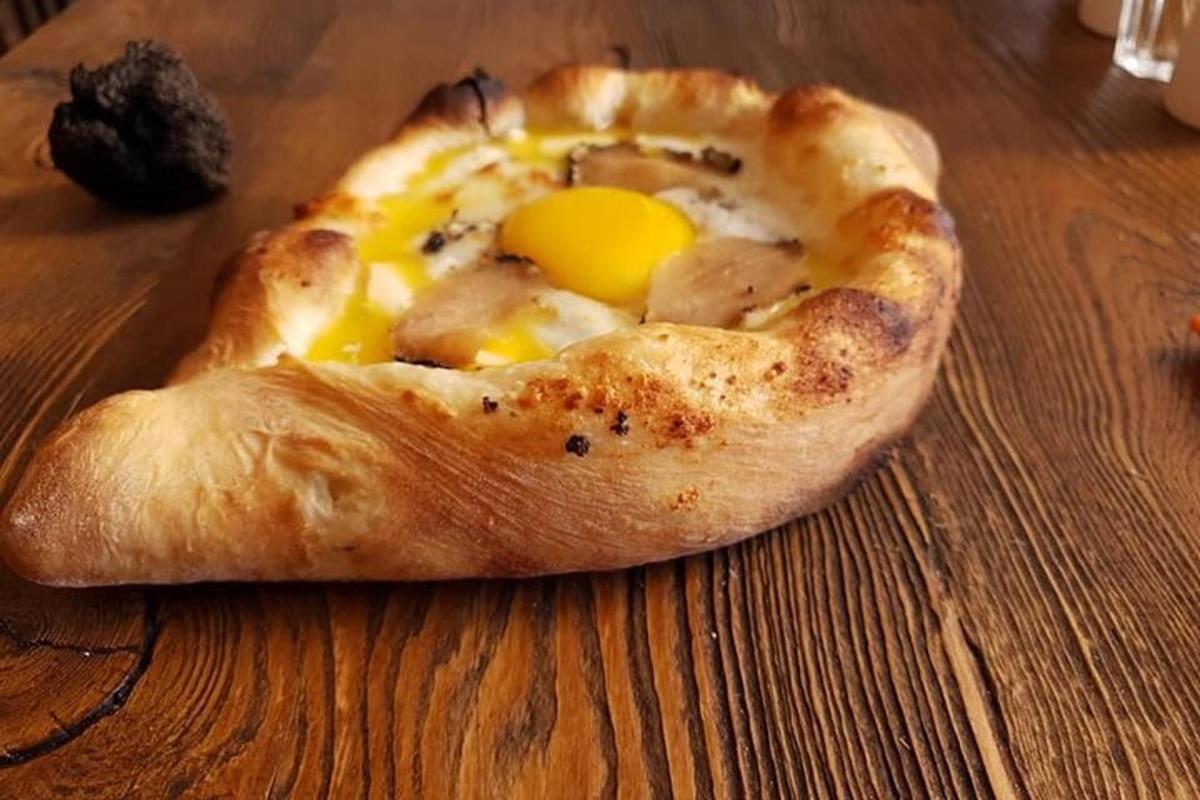 a small pizza with an egg on a wooden table