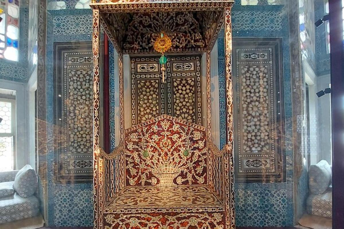 Una gran silla dorada en una habitación con una pared