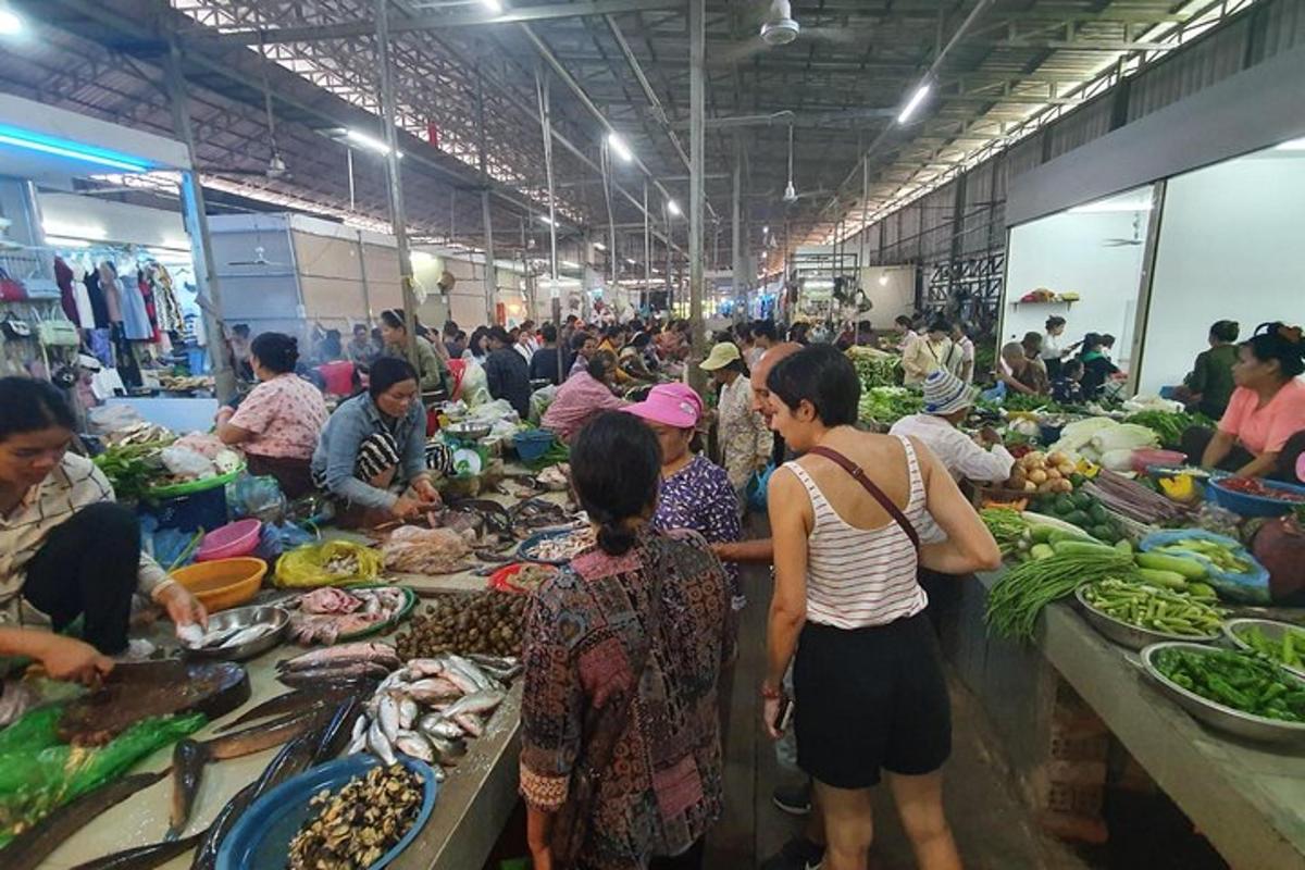 Un grupo de personas de pie en un mercado con verduras.