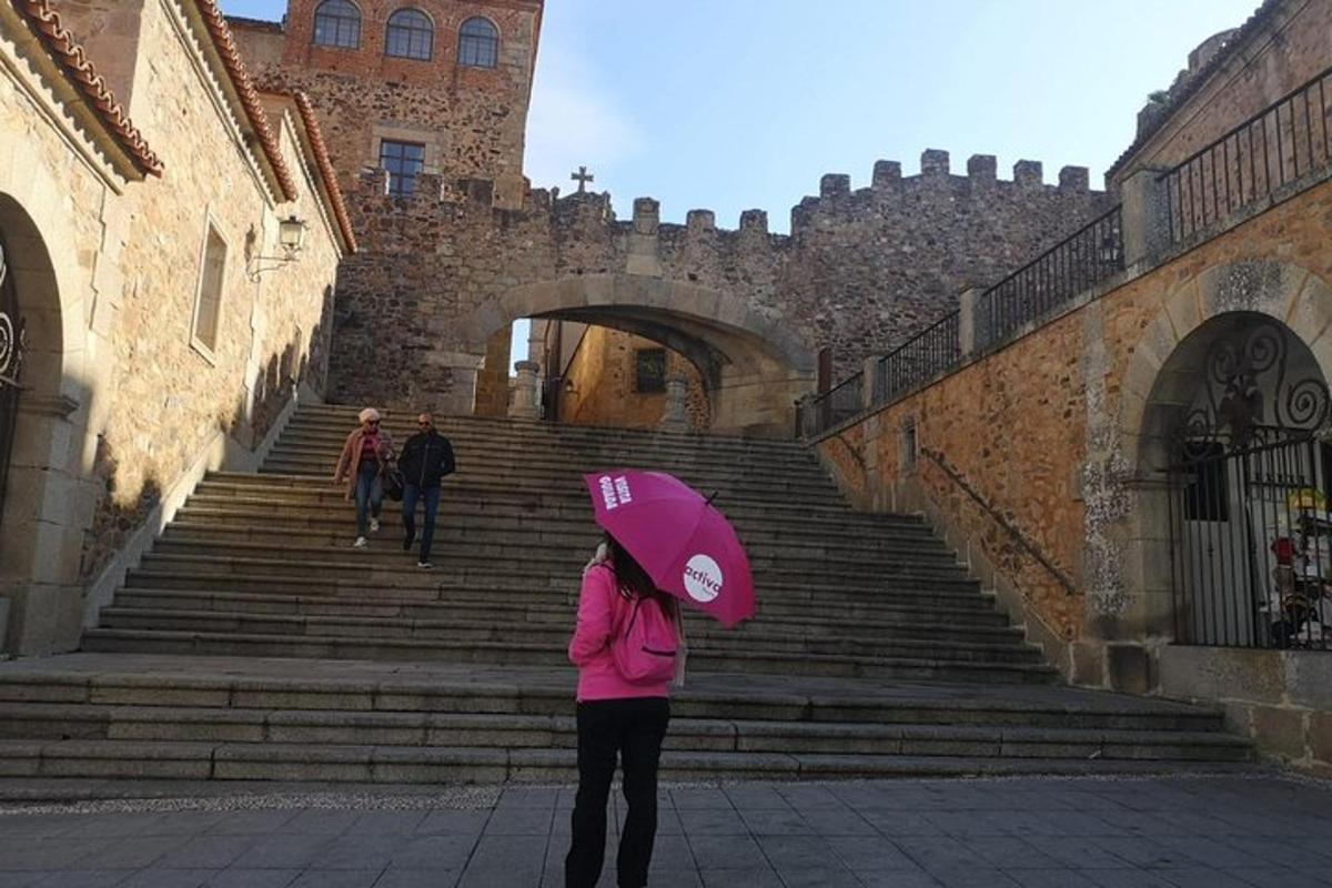 a woman with a pink umbrella standing in front of some stairs