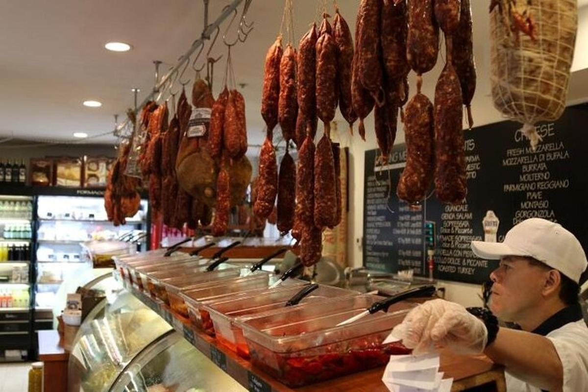 一名男子站在商店柜台前，柜台上挂着肉