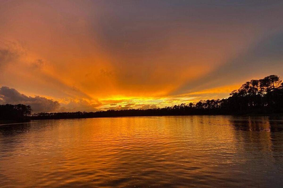 a sunset over a body of water with trees