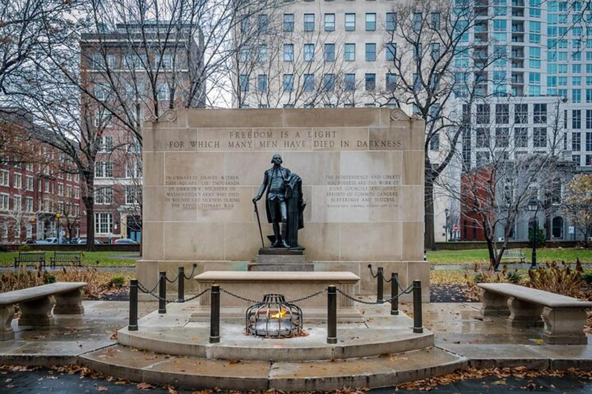 a statue in a park with buildings in the background