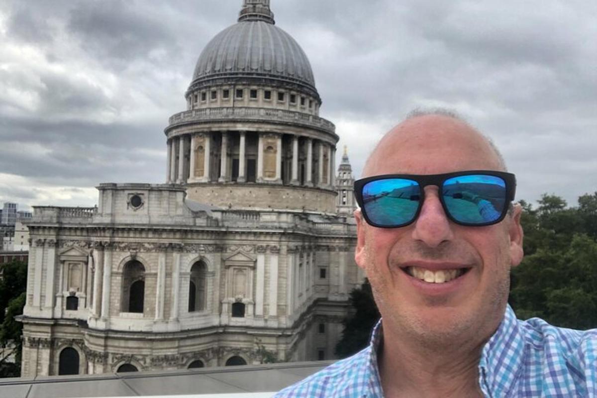 a man wearing sunglasses standing in front of a building