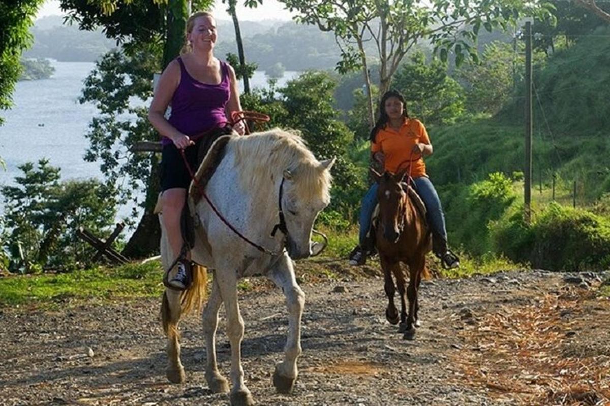 Dos mujeres montando a caballo y una vaca en un camino de tierra