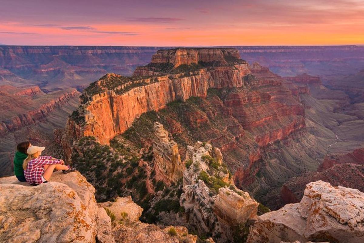 a person sitting on the edge of the grand canyon
