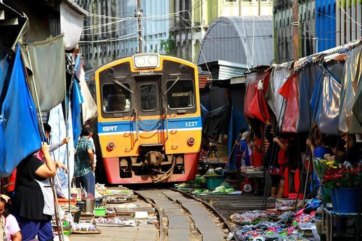 kereta api yang melalui pasar dengan orang ramai berdiri di sekelilingnya