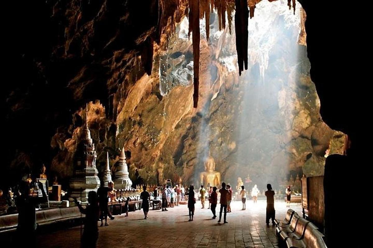 un gruppo di persone che camminano intorno a una statua in una grotta