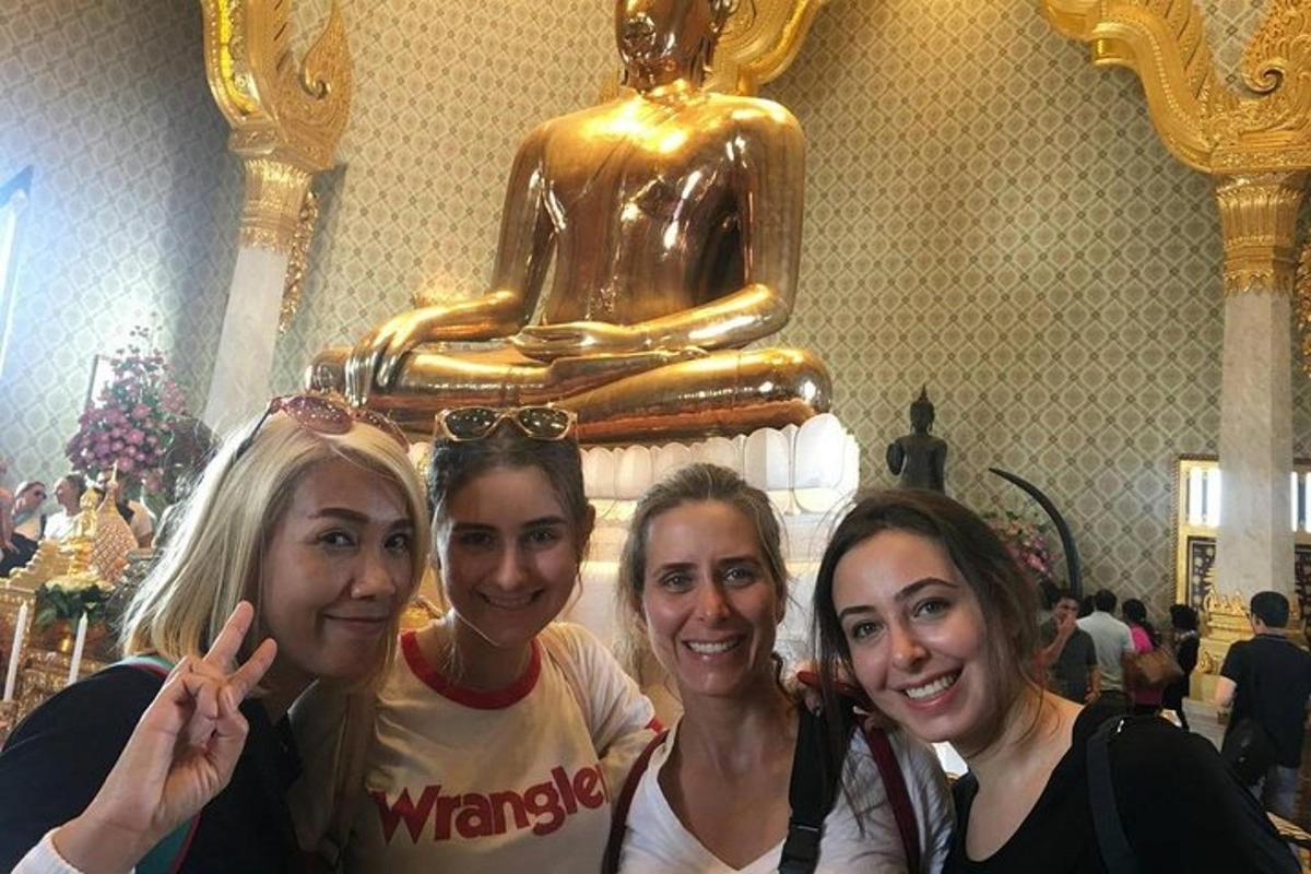 tre donne in posa davanti a una statua dorata