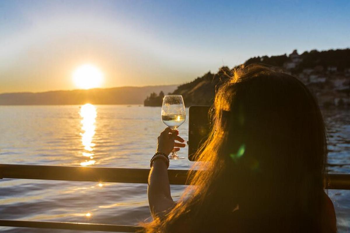 a woman holding up a glass of wine at sunset