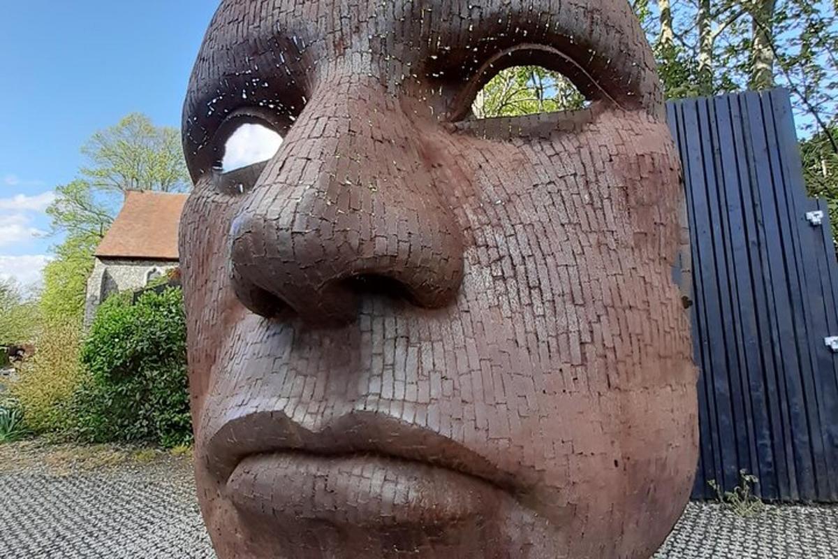 a statue of a mans face in front of a fence