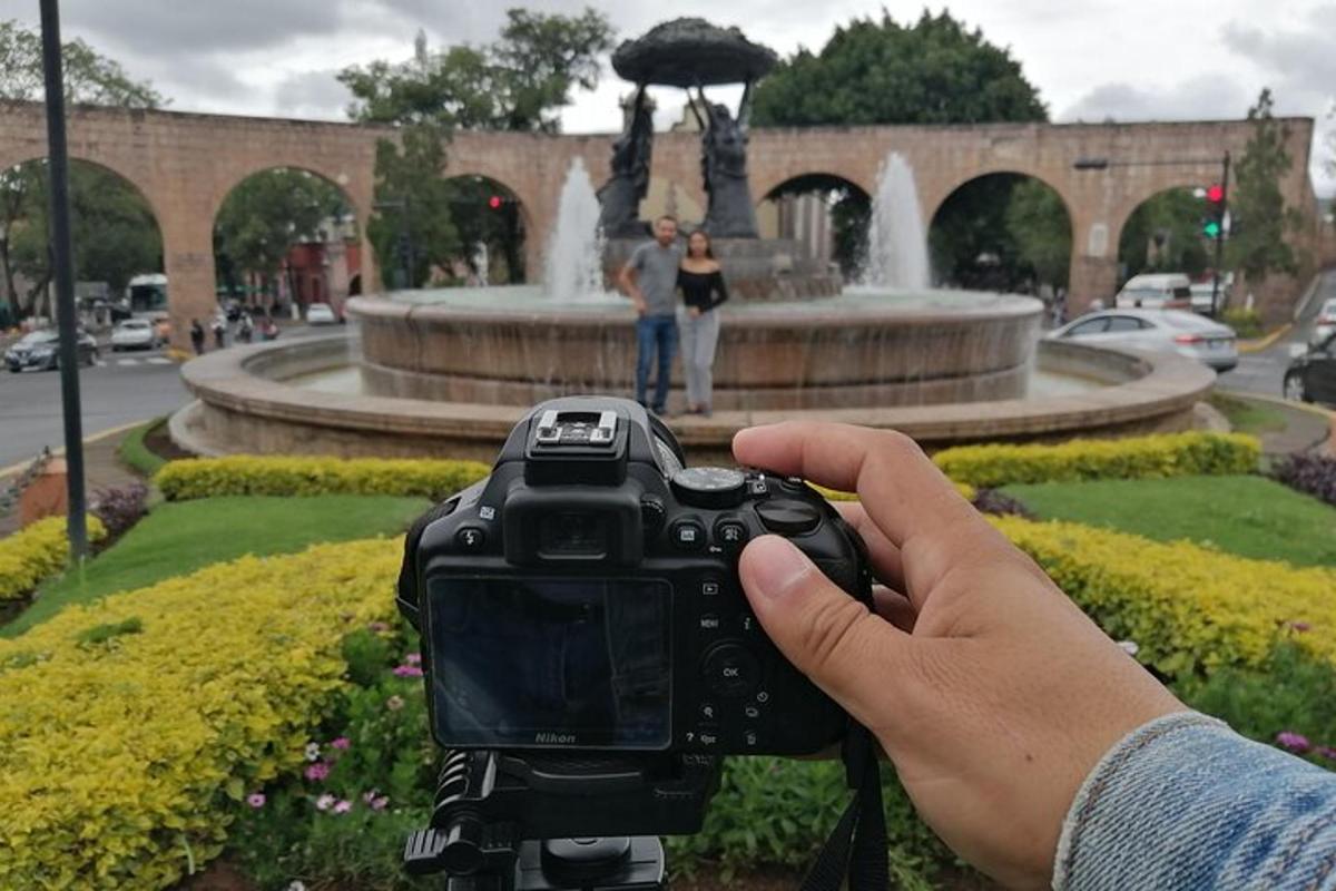 a person holding a camera in front of a fountain