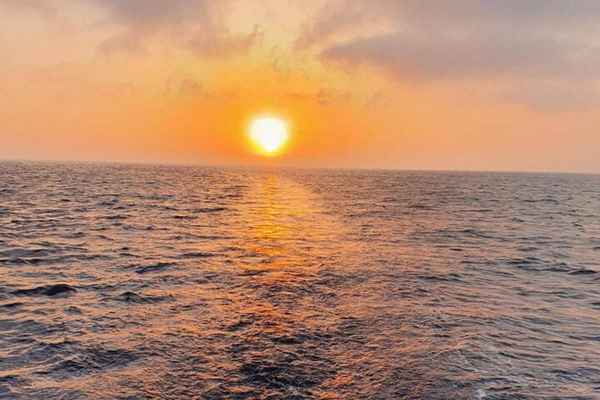 um pôr do sol sobre o oceano com o sol no céu