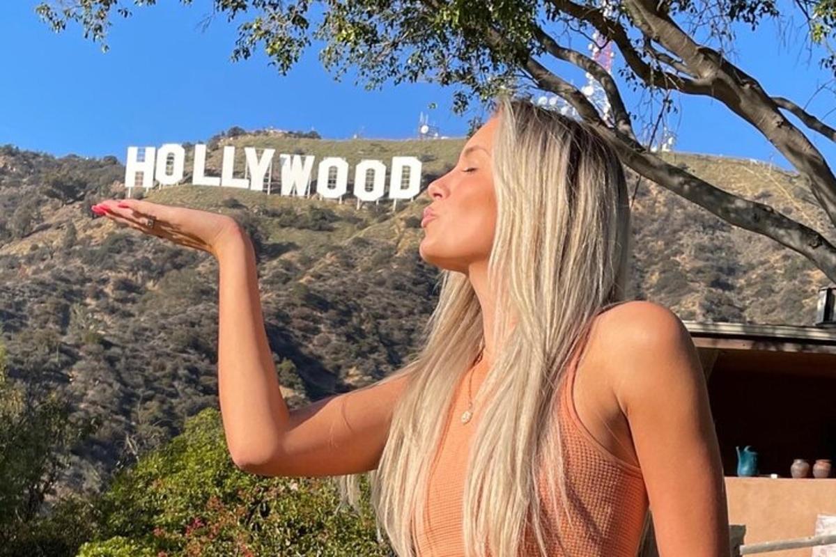 una donna in piedi davanti a un cartello di Hollywood