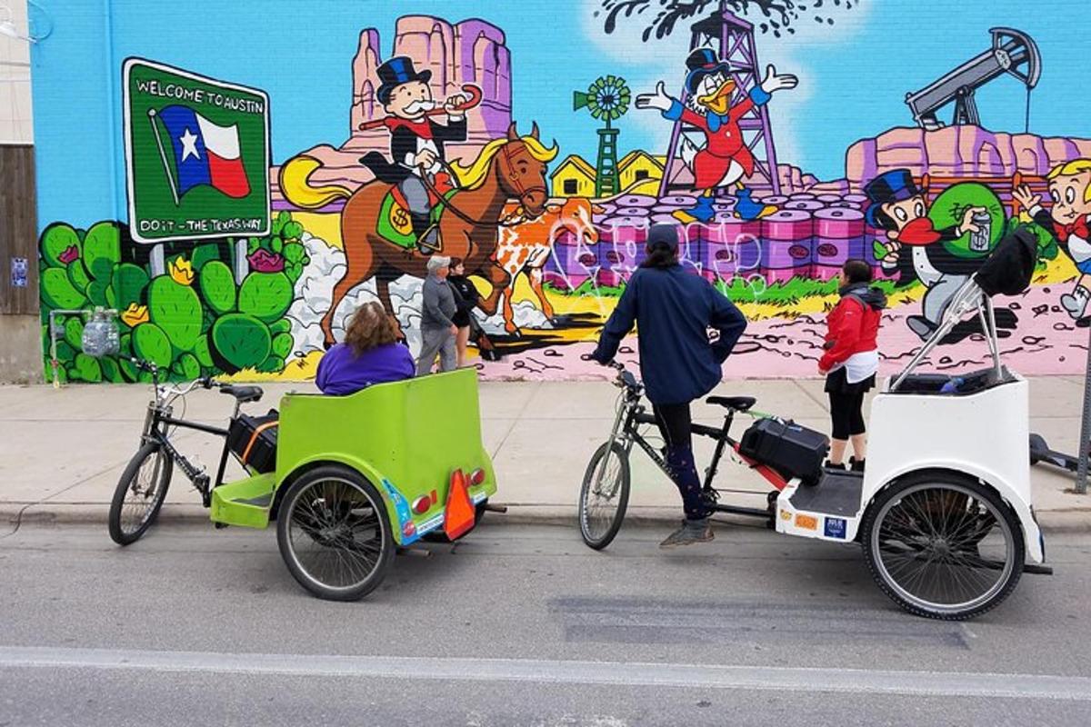 a group of people on bikes with a cart and a mural