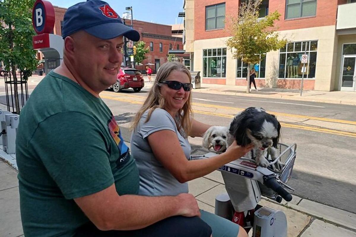 a man and a woman riding a motorcycle with two dogs