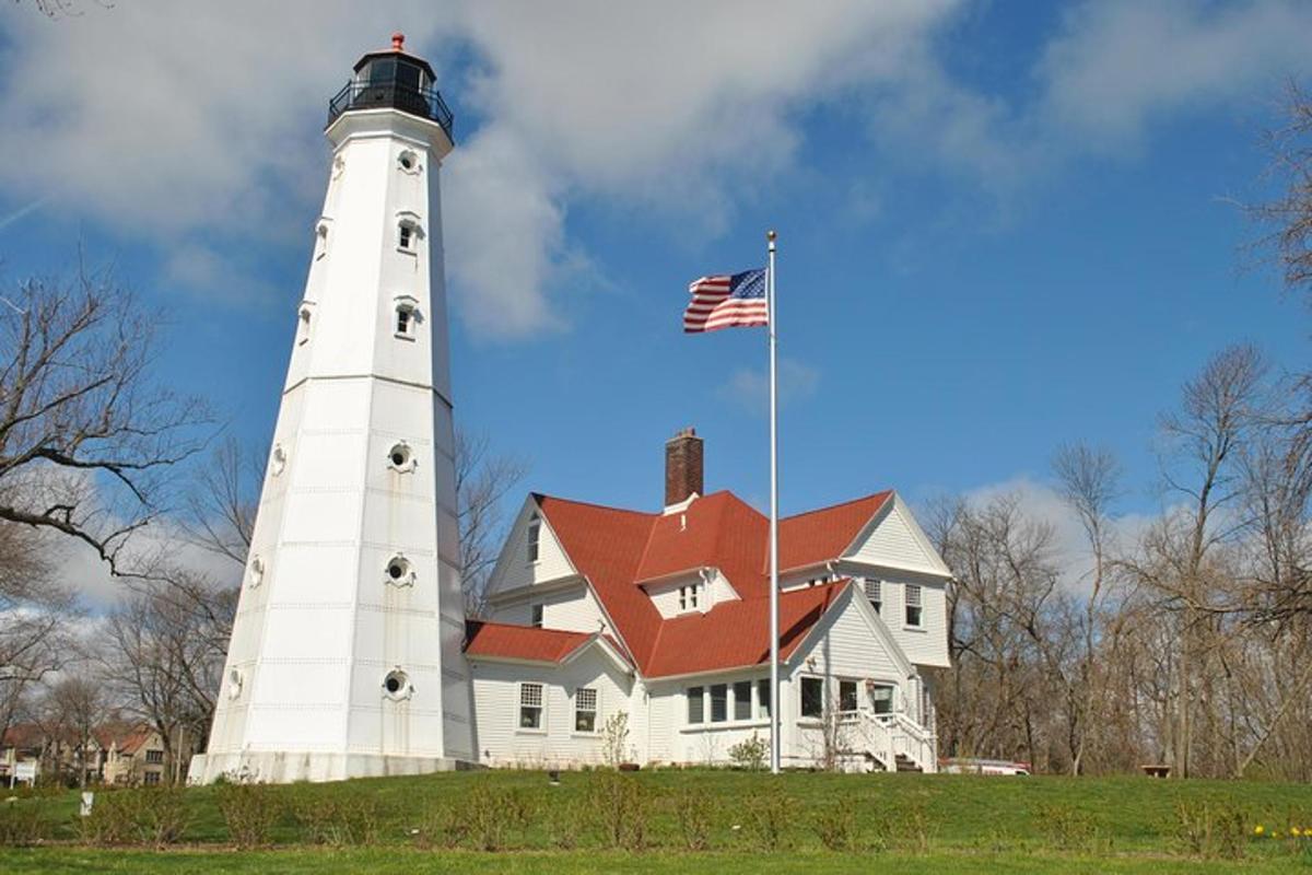 a lighthouse with an american flag in front of a house
