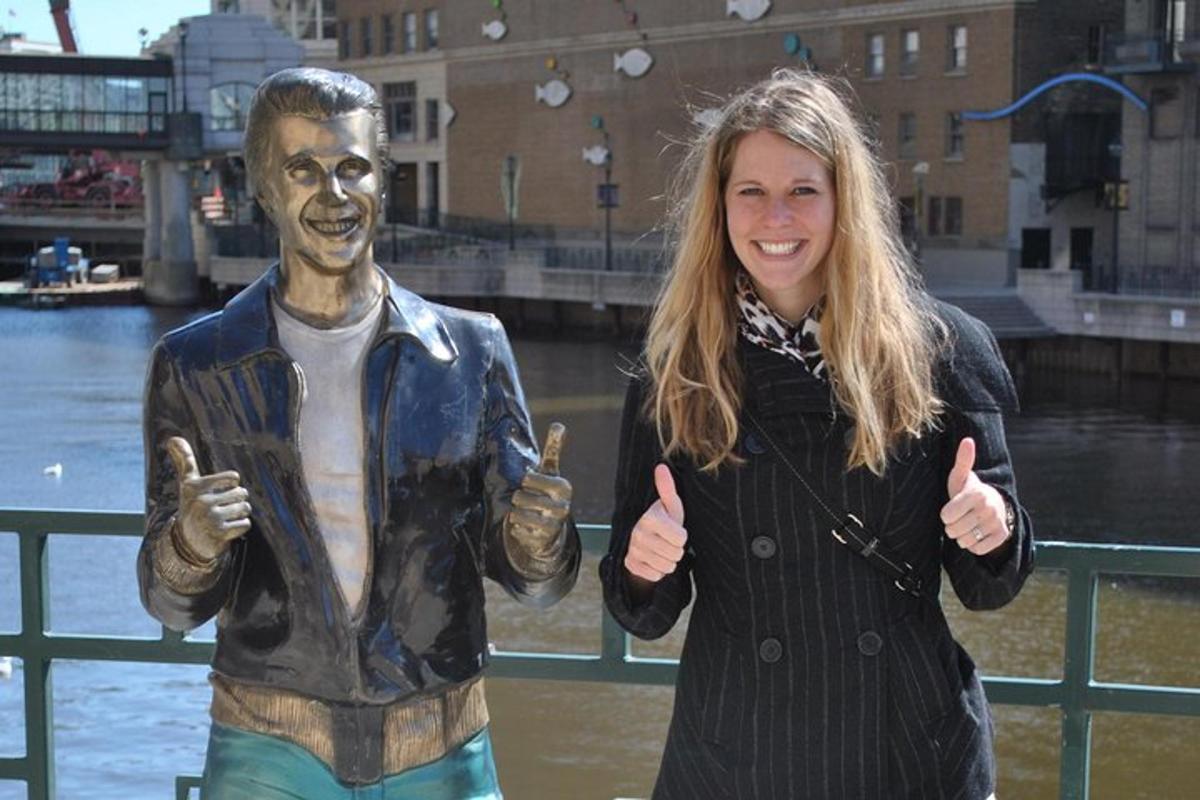 a woman giving a thumbs up next to a statue