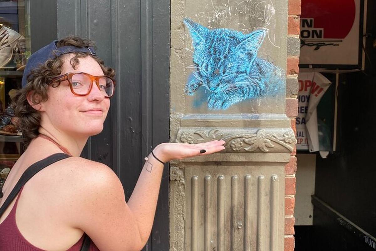 a woman standing next to a wall with a cat painted on it